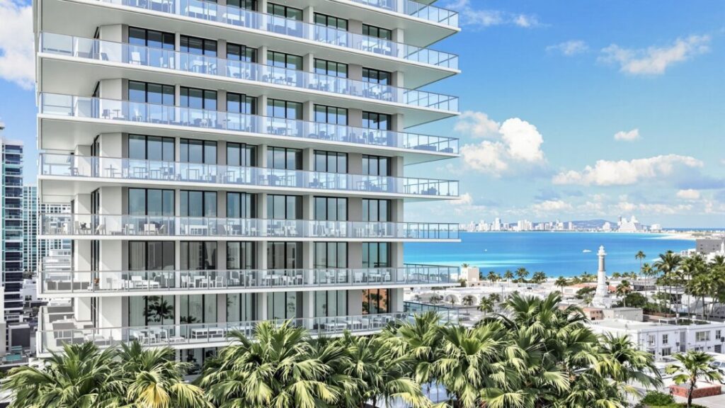 Modern skyscraper with glass balconies overlooking Miami cityscape and water.