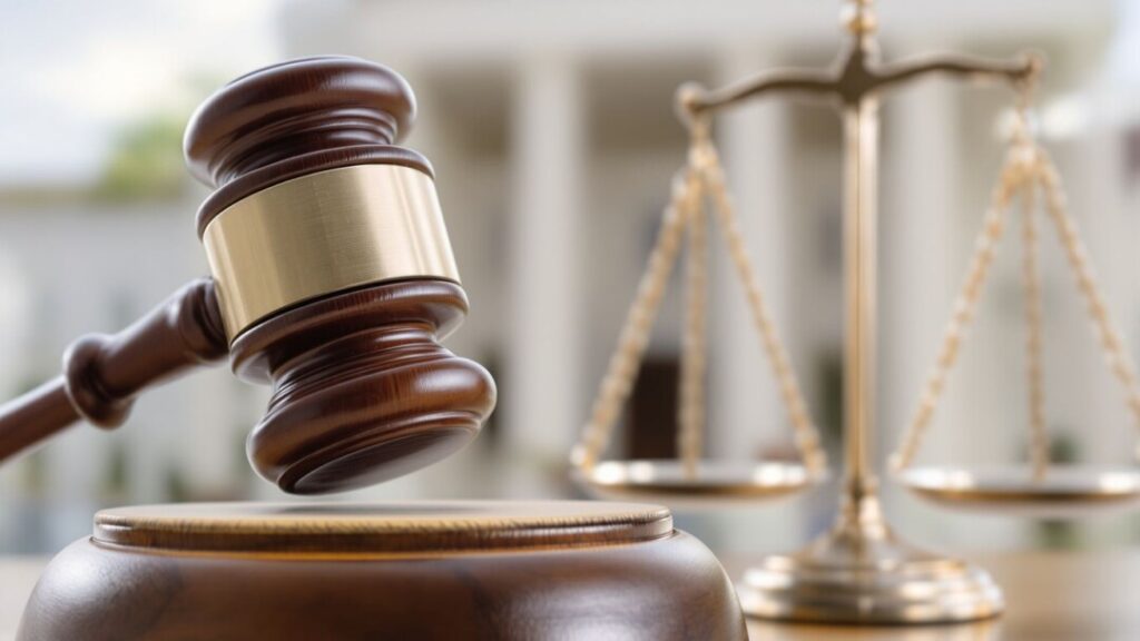 Gavel striking block near courthouse, legal dispute imagery.