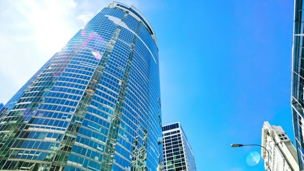 Modern skyscraper with glass facade against blue sky.