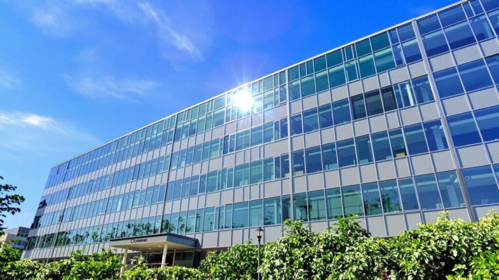 Modern office building exterior with blue sky and landscaping.
