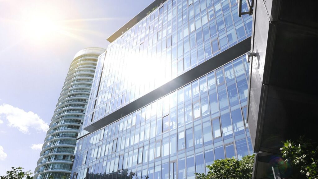 Modern office building exterior with clear sky and greenery.