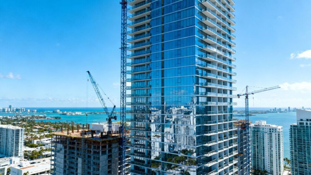 Miami skyscraper construction with cranes and city skyline.