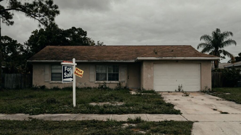 Florida house with price reduced sticker, overcast sky.