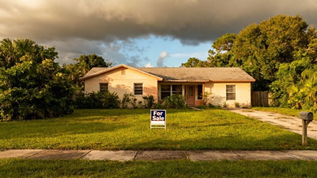 Florida house for sale with yard and cloudy sky.