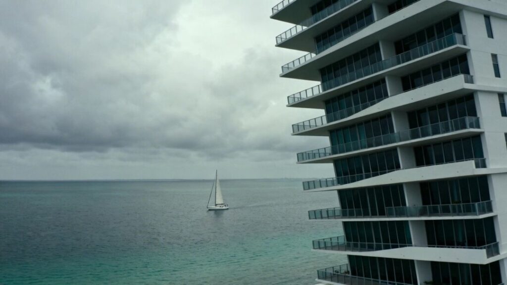 Miami condo tower with ocean view, overcast sky.