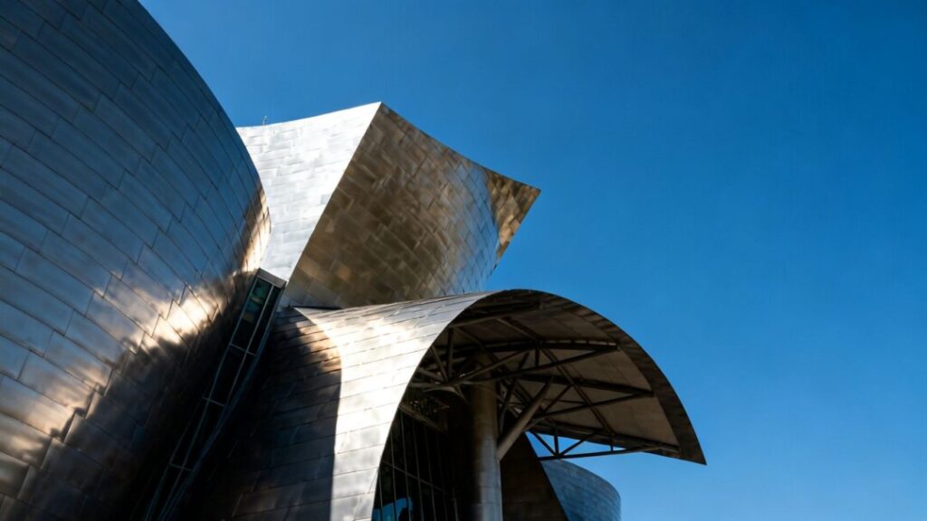 [Frank Gehry] building's metallic, sculptural facade against a sky.