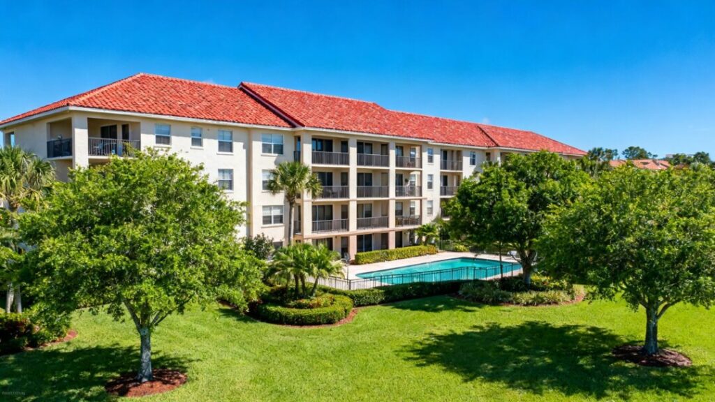 Modern apartment building with red roof and green landscaping.
