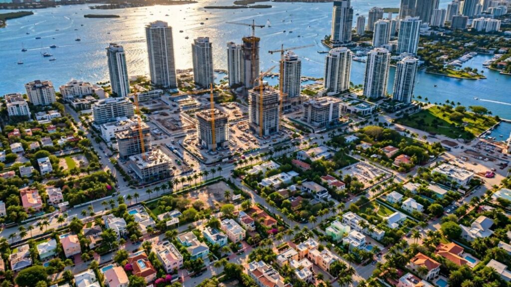 Miami waterfront skyline with condos, homes, palms, and construction cranes